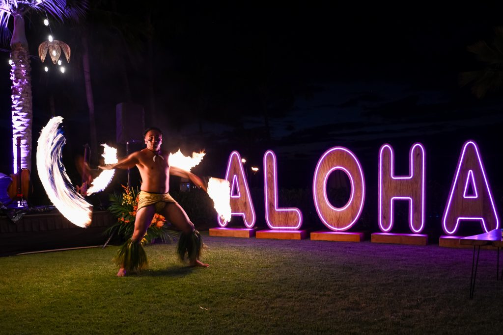 fire dancer in front of "Aloha" sign